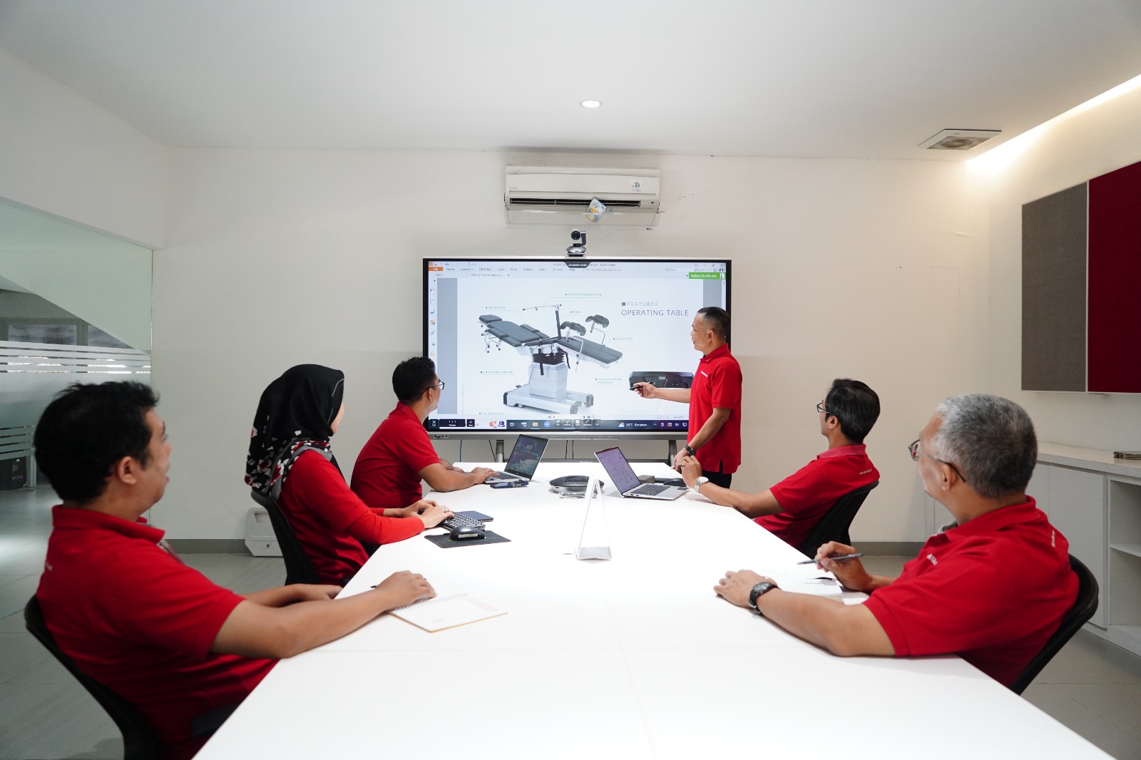 Four construction workers wearing helmets and uniforms, standing outdoors with trees in the background